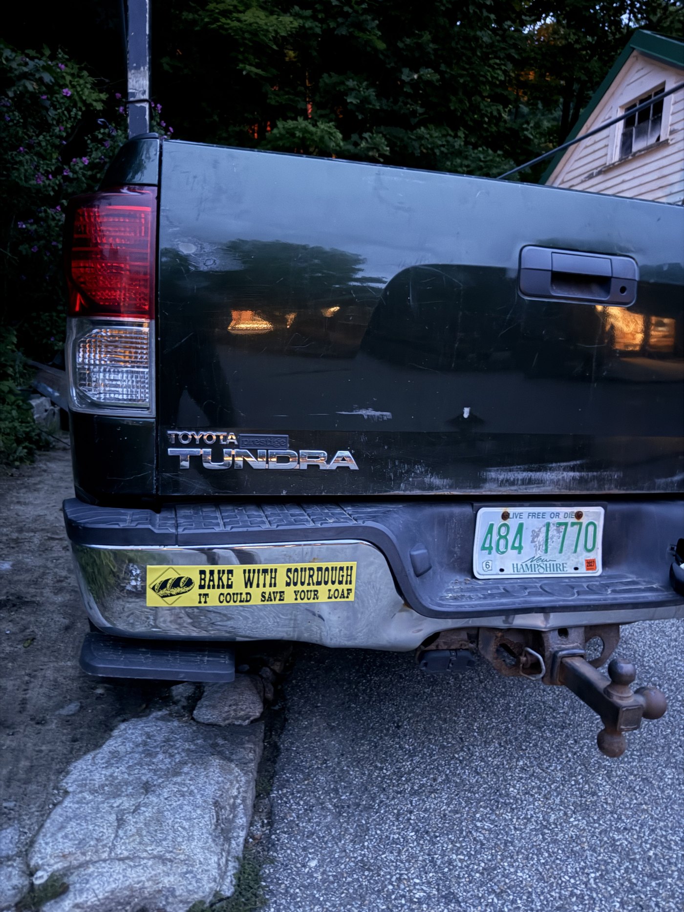 The BAKE WITH SOURDOUGH magnet on the chrome bumper of a green Toyota Tundra